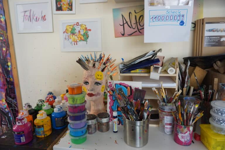 Kreative Mantis-Dekoration aus bunten Farben und Materialien auf einem Basteltisch.