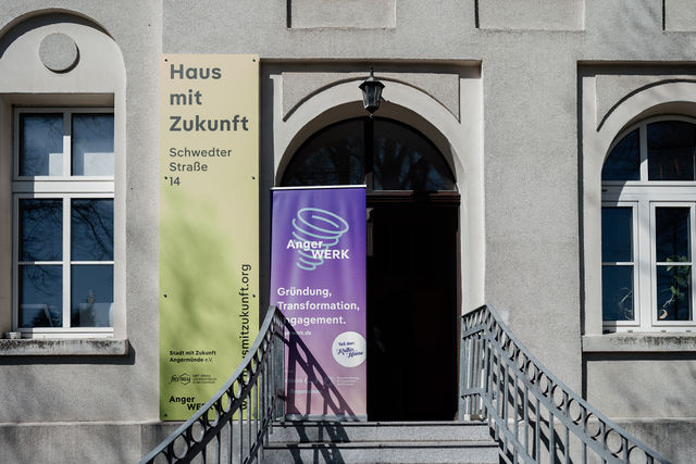 Gebäude des AngerWERK mit Eingangsportal und Bannern, Fokus auf nachhaltige Stadtentwicklung.