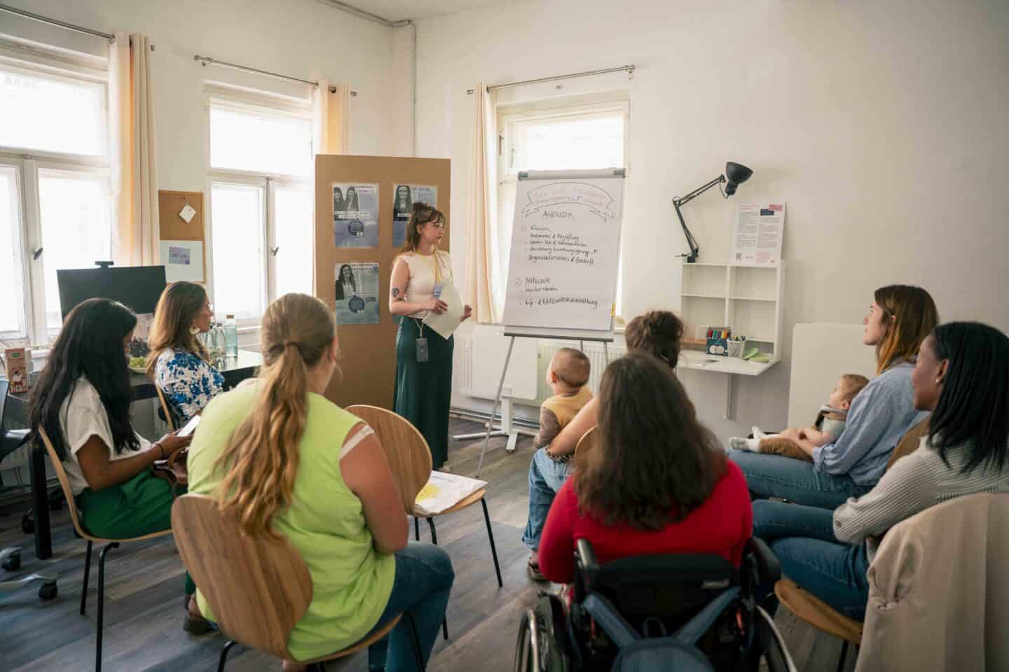 Workshop mit Lehrerin und Teilnehmern in einem hellen Raum.