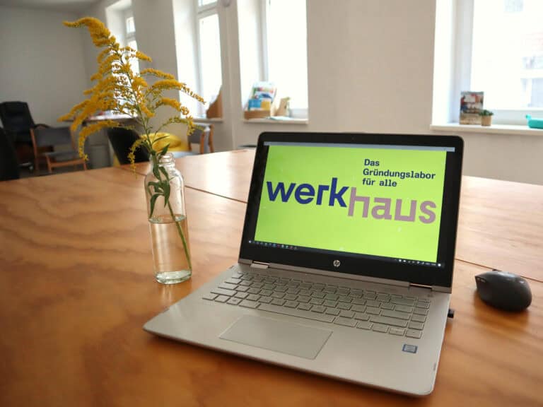 Laptop auf einem Tisch im Gründerlabor mit Pflanzen und Fenster im Hintergrund.