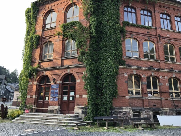 Historisches Lauscha-Gebäude mit grüner Kletterpflanze an der Fassade.