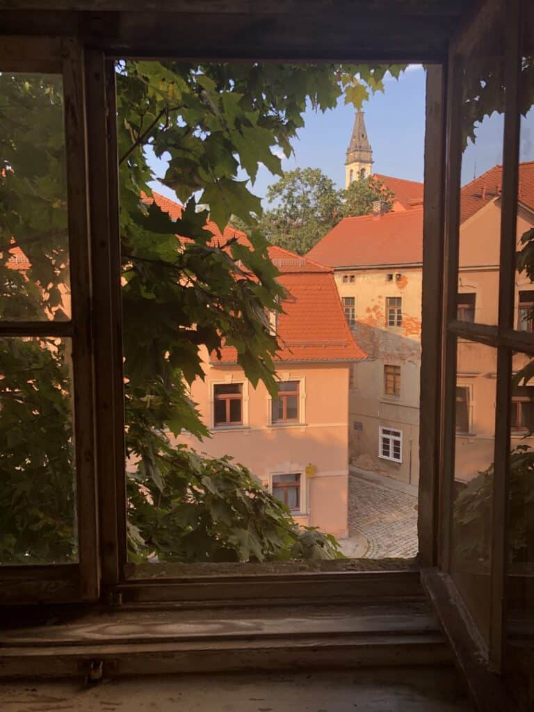 Blick durch ein Fenster auf die Altstadt von Zschopau mit Kirchturm im Hintergrund.