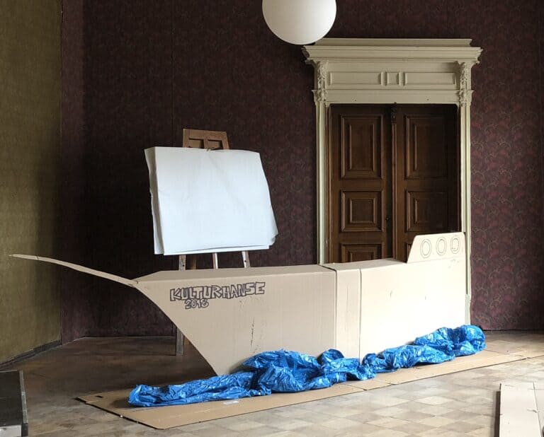 Pappschiff mit blauen Dekorationen im Raum, als kreative Raumgestaltung.