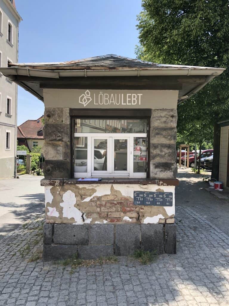 Kleiner Kiosk in Löbau mit moderner Beschilderung und alter Fassade.