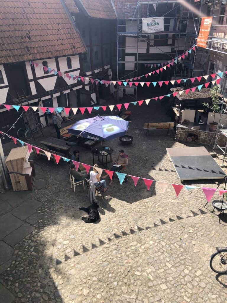 Innenhof in Salzwedel mit bunten Girlanden, Tischen und Sitzgelegenheiten.