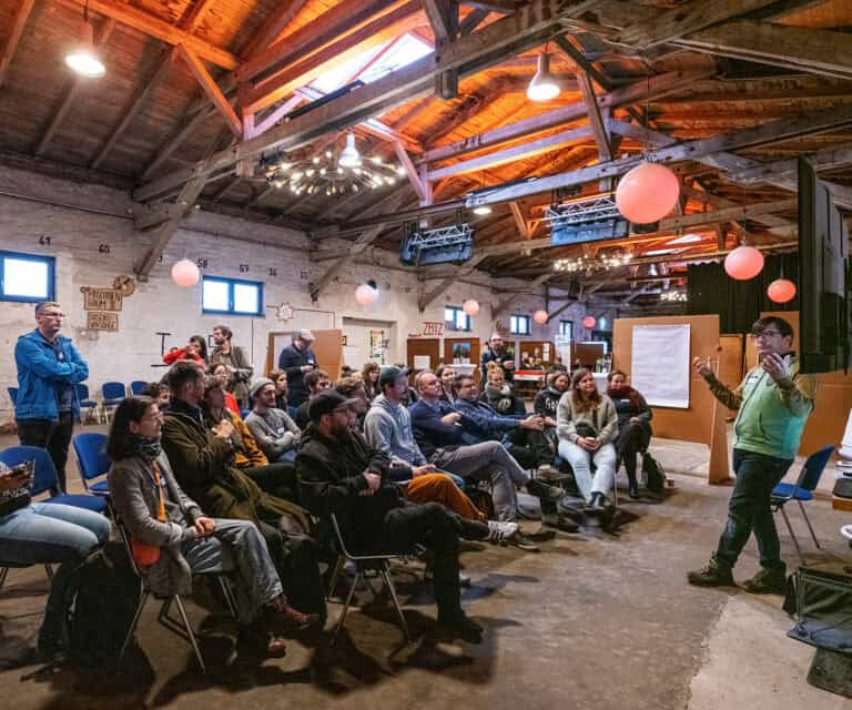 Menschen bei einem Workshop in einem rustikalen, gut beleuchteten Raum mit Holzdecke und moderner Be.