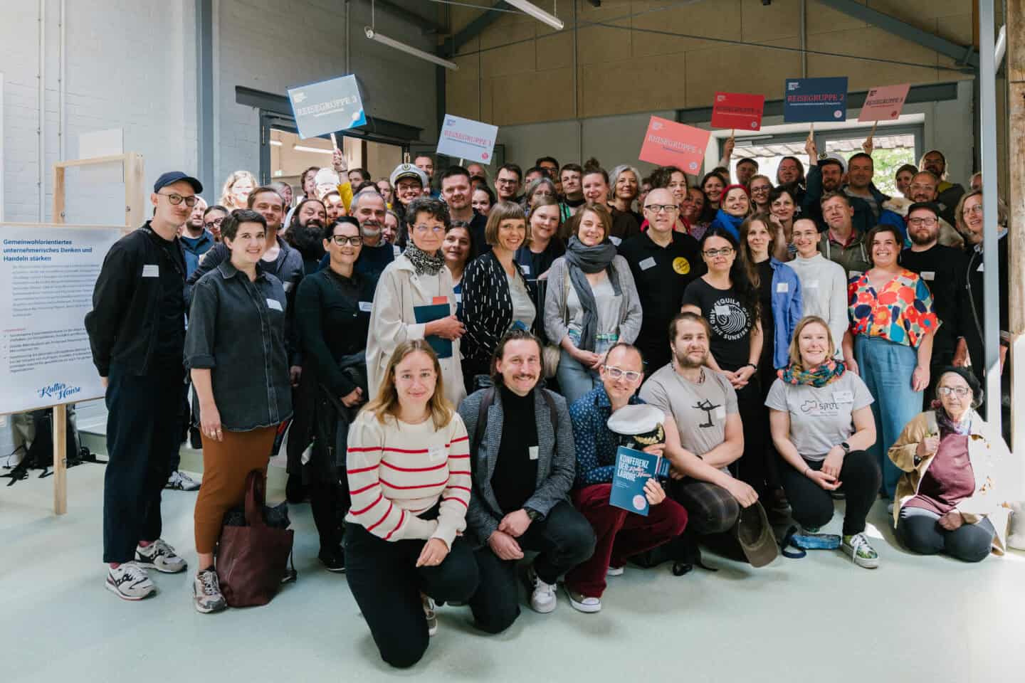 Große Gruppe von Menschen bei einer Veranstaltung in einem modernen Raum.