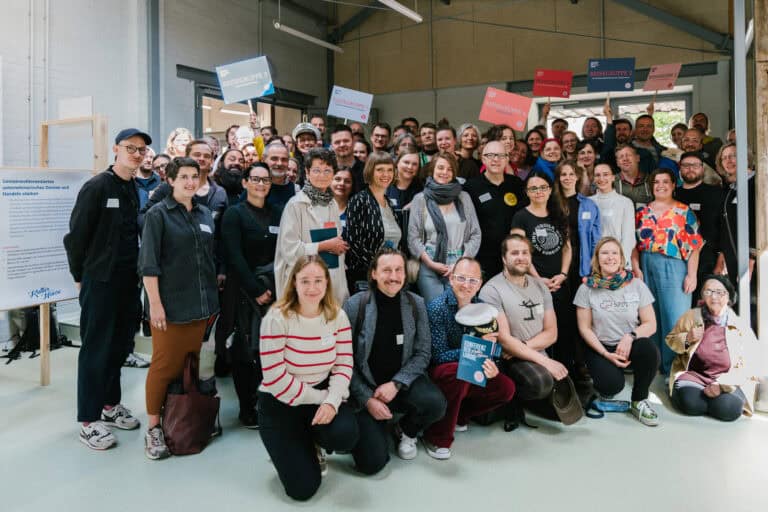 Große Gruppe von Menschen bei einer Veranstaltung in einem modernen Raum.