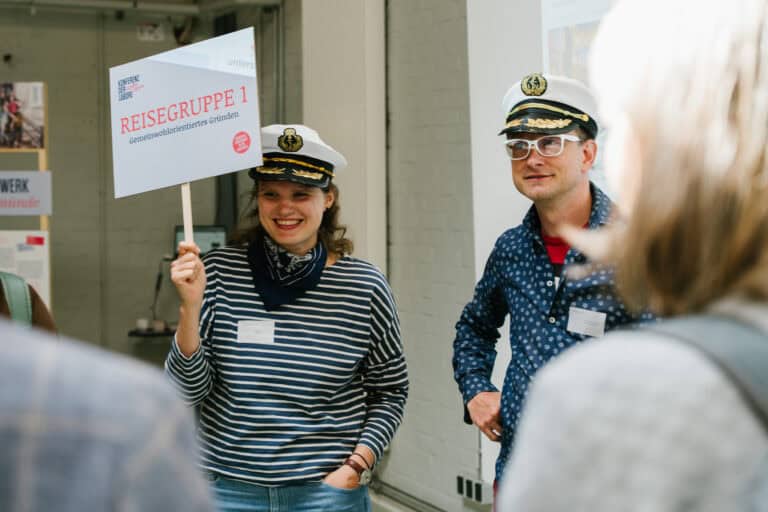 Reisegruppe mit Kapitänshut bei einer Tour, lächelnd und im Gespräch.