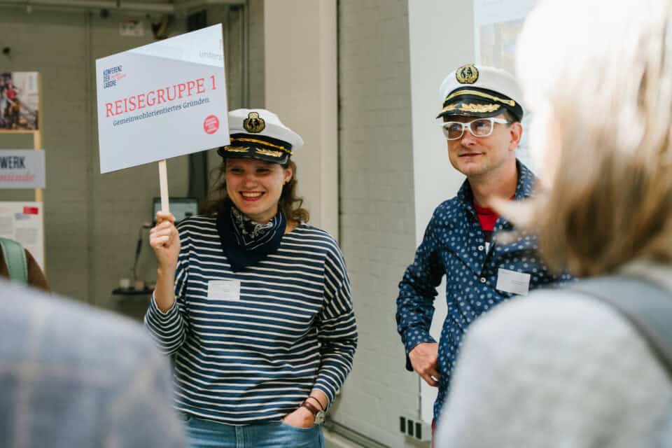 Reisegruppe mit Kapitänshut bei einer Tour, lächelnd und im Gespräch.