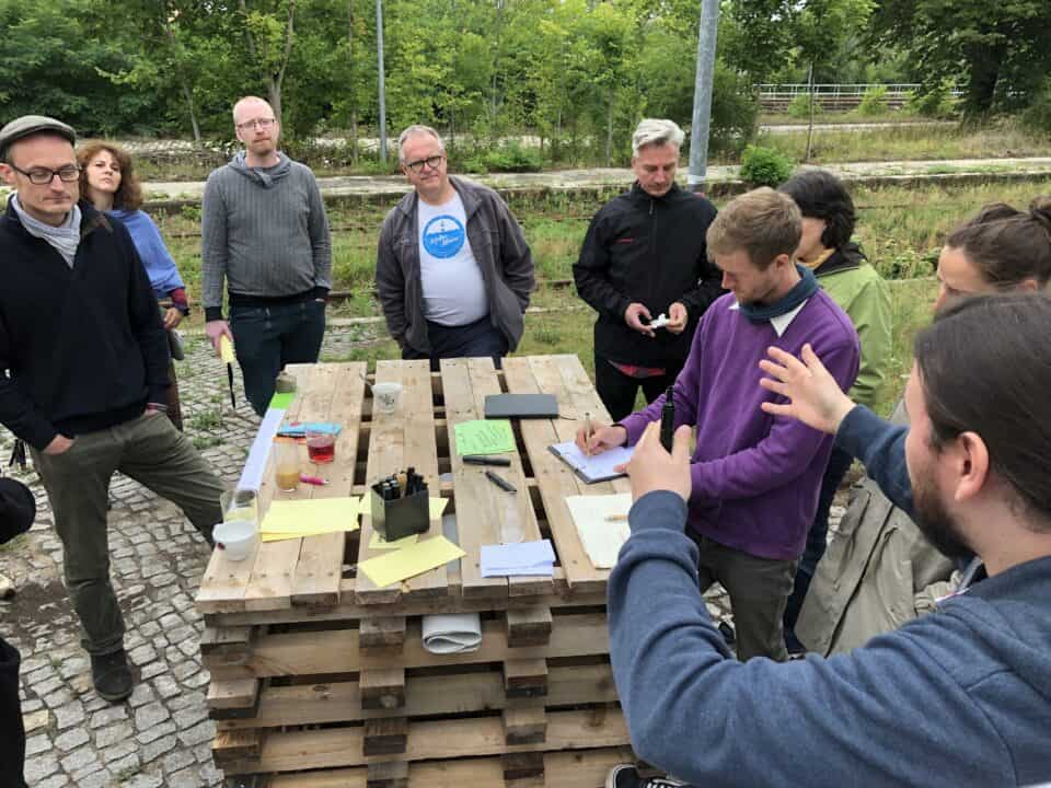 Gruppe von Menschen bei Baumpflanzung im Park, umgeben von Natur.