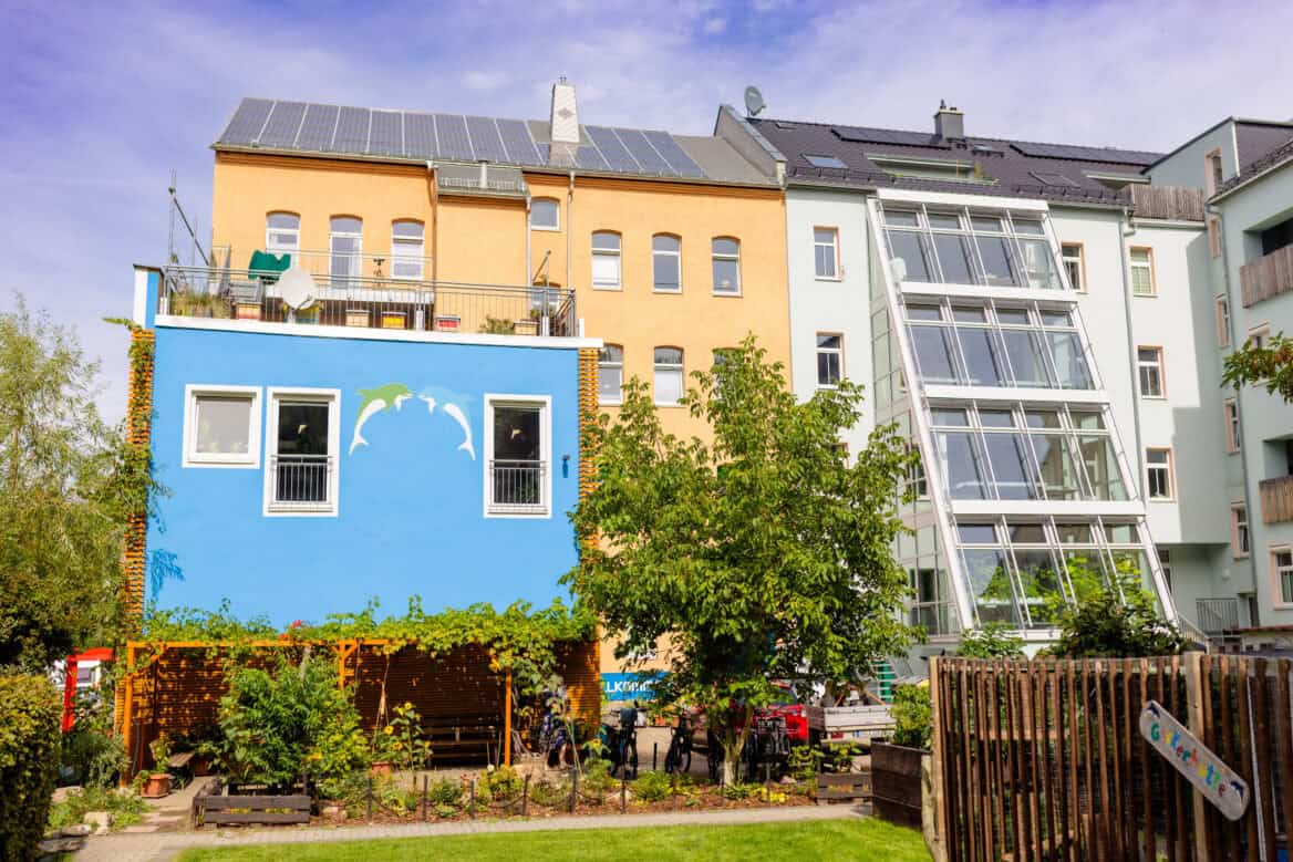 Bunte Wohnhäuser mit Solaranlagen und begrüntem Garten in KARREE49.