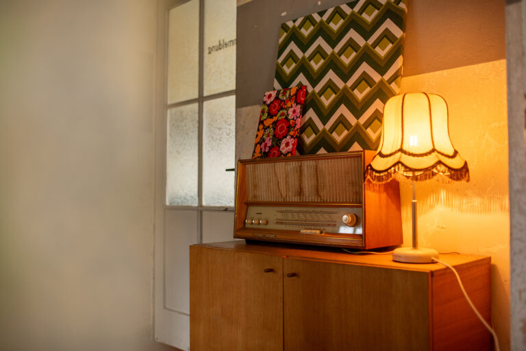 Vintage-Radio auf einem Holzschrank mit dekorativen Kissen und warmem Lampenlicht.
